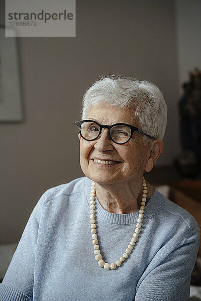 Glückliche ältere Frau mit Brille  die zu Hause zwinkert