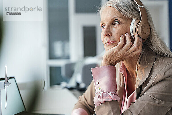 Geschäftsfrau hört im Büro Musik über Kopfhörer