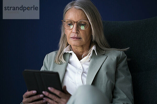 Geschäftsfrau nutzt Tablet-PC vor blauem Hintergrund