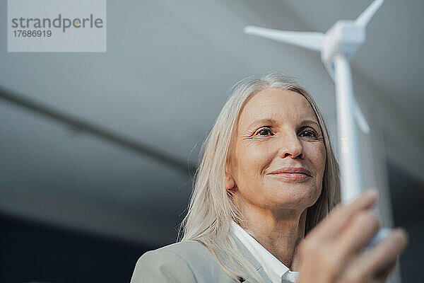 Ältere Geschäftsfrau mit Windturbinenmodell im Büro