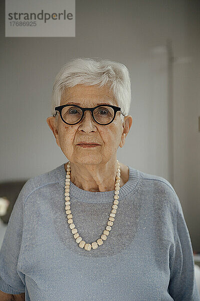 Lächelnde ältere Frau mit weißen Haaren  die zu Hause steht