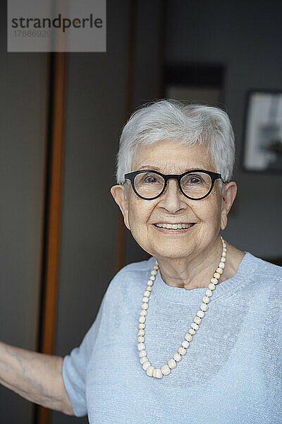 Lächelnde ältere Frau mit weißen Haaren in der Wohnung