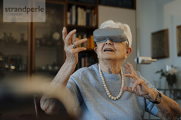 Ältere Frau mit Virtual-Reality-Simulator sitzt zu Hause