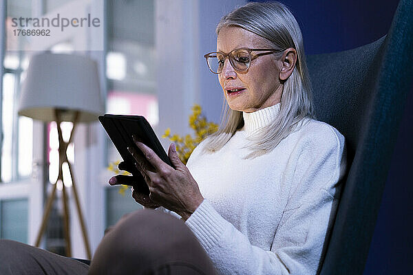 Ältere Frau mit Brille nutzt Tablet-PC zu Hause