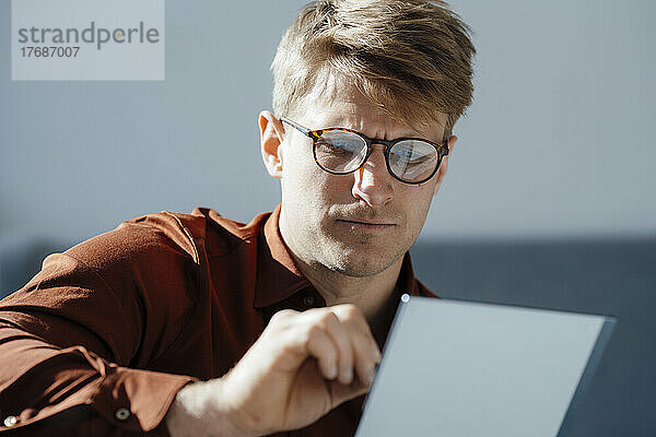 Geschäftsmann mit Brille arbeitet im Büro am Tablet-PC