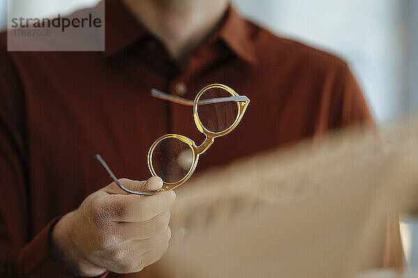 Hand eines Geschäftsmannes mit Brille im Büro