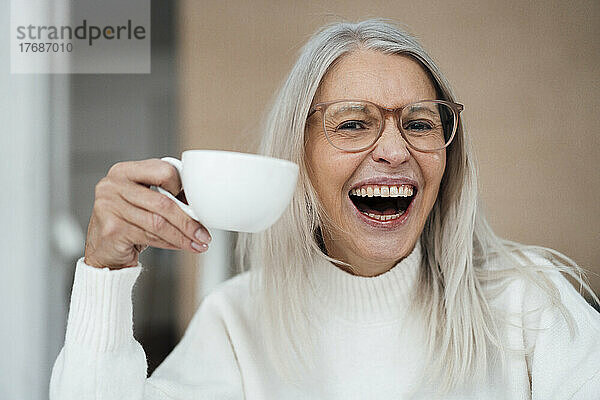 Fröhliche ältere Frau hält Kaffeetasse