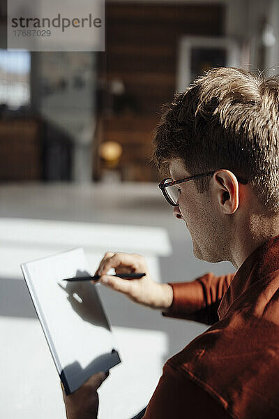 Geschäftsmann mit digitalisiertem Stift schreibt auf Tablet-PC im Büro