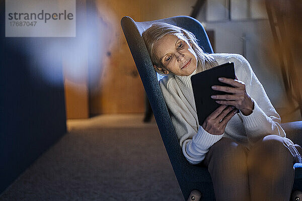 Ältere Frau benutzt einen Tablet-PC  der auf einem Stuhl ruht