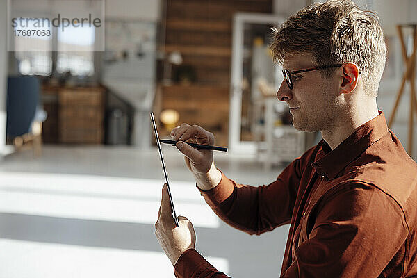 Geschäftsmann hält digitalisierten Stift mit Tablet-PC im Büro