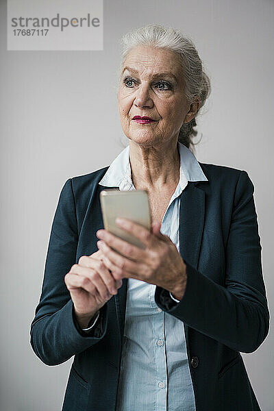 Geschäftsfrau mit Smartphone vor weißem Hintergrund