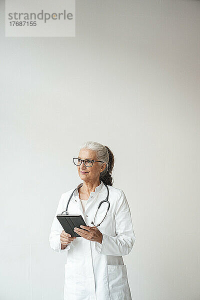 Leitender Arzt mit Tablet-PC vor weißem Hintergrund