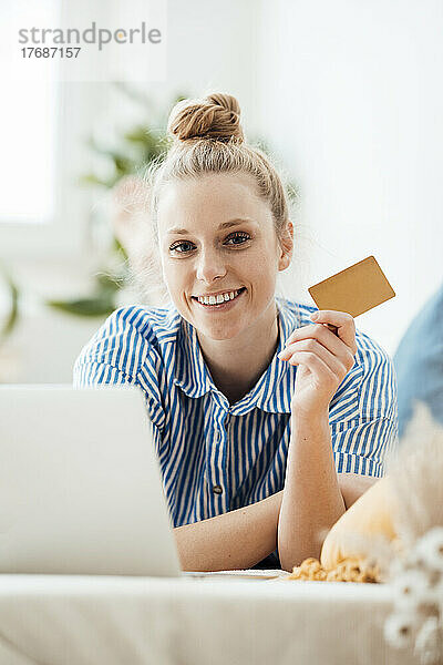 Geschäftsfrau zeigt Kreditkarte im Liegen zu Hause