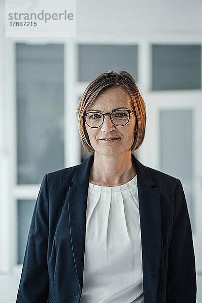 Smiling businesswoman wearing eyeglasses standing at office