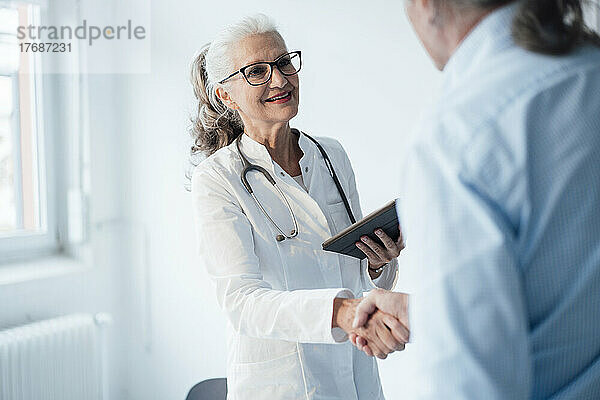 Lächelnder Oberarzt schüttelt dem Patienten die Hand