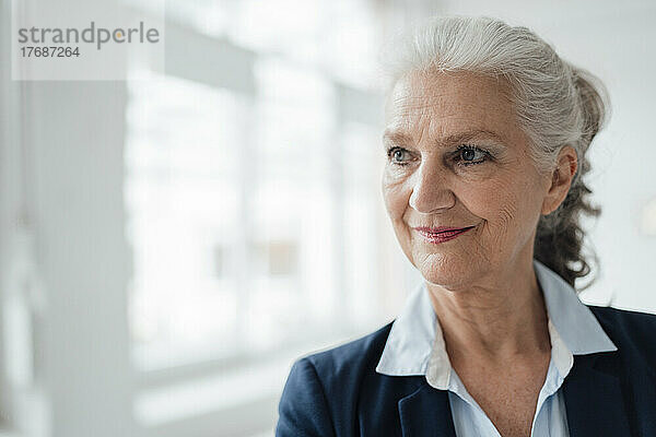 Lächelnde ältere Geschäftsfrau mit grauen Haaren im Büro
