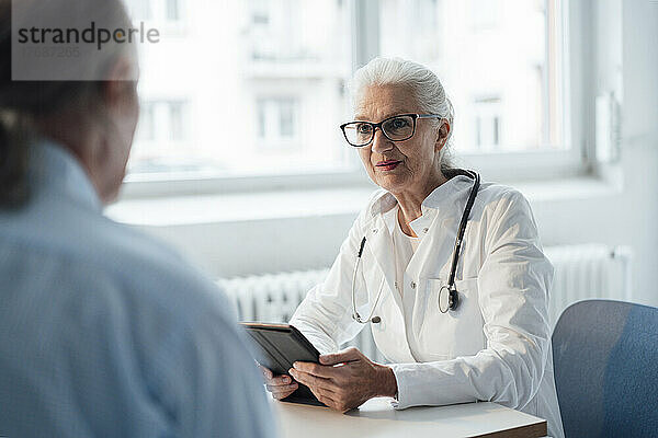 Arzt bespricht sich mit Patient  der am Schreibtisch sitzt