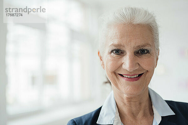Glückliche ältere Geschäftsfrau mit grauen Haaren im Büro