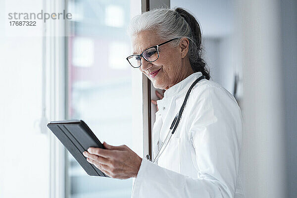 Glücklicher Arzt mit Brille und Tablet-PC