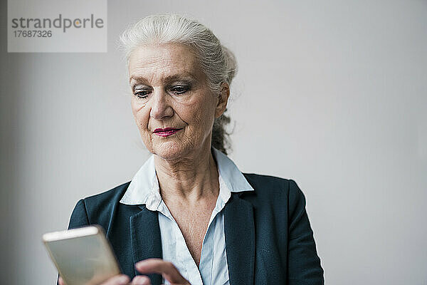 Geschäftsfrau benutzt Smartphone vor weißem Hintergrund