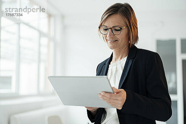 Glückliche Geschäftsfrau nutzt Tablet-PC im Büro