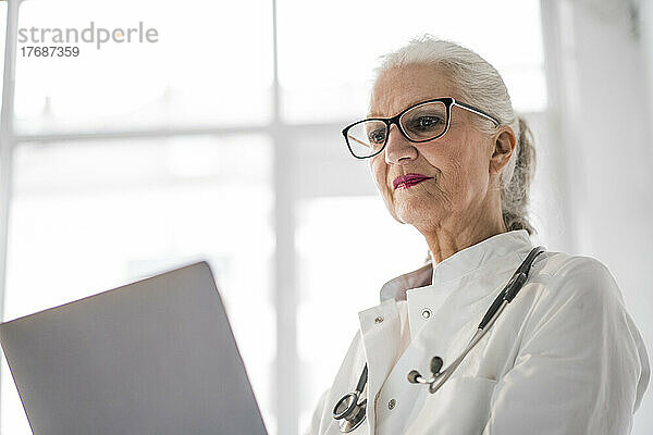 Oberarzt mit Brille und Laptop