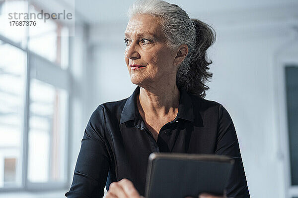 Ältere Geschäftsfrau mit Tablet-PC sitzt im Büro