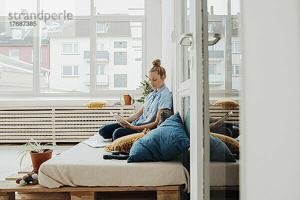 Geschäftsfrau liest Buch und sitzt zu Hause im Bett