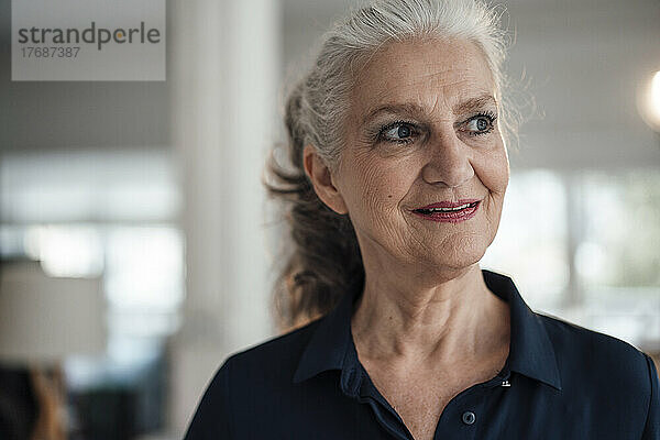 Lächelnde ältere Geschäftsfrau mit grauen Haaren  die im Büro steht