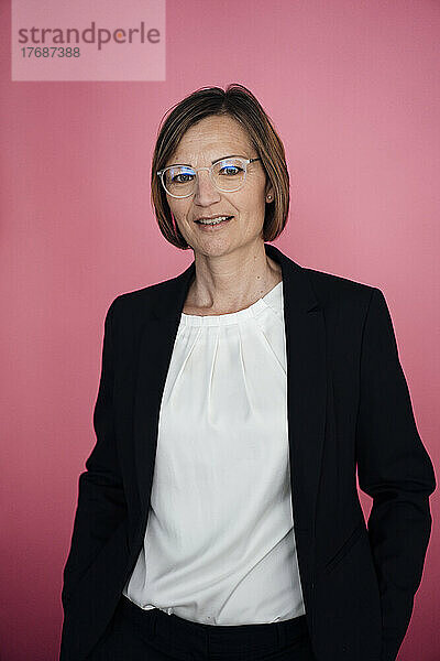 Geschäftsfrau mit Brille vor rosa Hintergrund