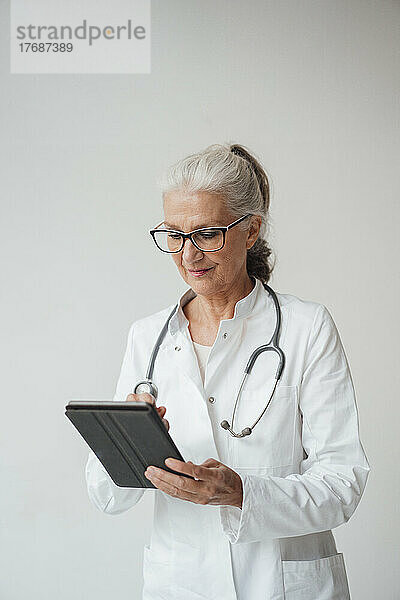 Oberarzt mit Tablet-PC vor weißem Hintergrund