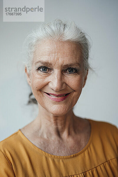 Glückliche ältere Frau mit grauen Haaren vor weißem Hintergrund