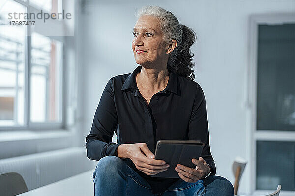 Ältere Geschäftsfrau mit Tablet-PC sitzt am Schreibtisch im Büro