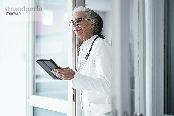 Glücklicher Arzt mit Brille und Tablet-PC