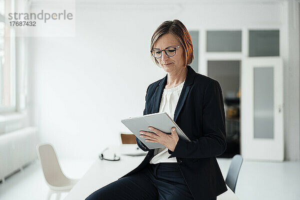 Geschäftsfrau sitzt am Schreibtisch im Büro und benutzt einen Tablet-PC