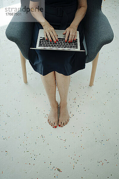 Geschäftsfrau benutzt Laptop im Sessel sitzend