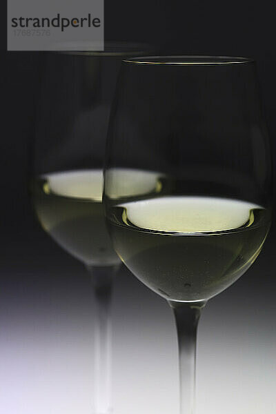 Glasses of white wine against black background