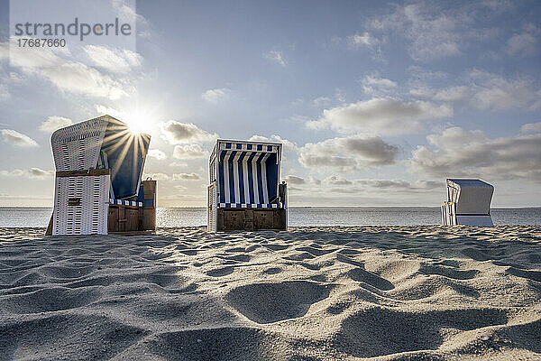 Deutschland  Schleswig-Holstein  Hörnum  Morgensonne scheint über leere Strandkörbe mit Kapuze  die am Sandstrand stehen