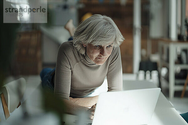 Ältere Frau benutzt Laptop und liegt auf dem Schreibtisch im Büro