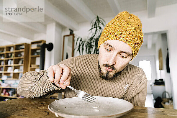 Hungry man scratching last rice corn from his plate