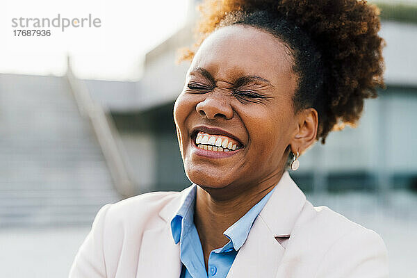 Afro-Geschäftsfrau lacht mit geschlossenen Augen