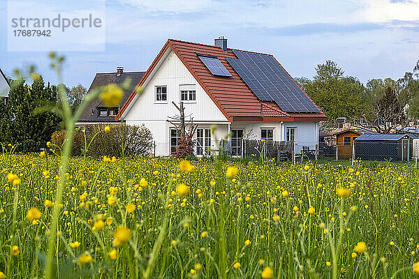 Sonnenkollektoren auf dem Dach eines Hauses neben der Wiese