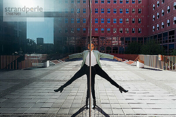 Spiegelbild einer Geschäftsfrau  die in der Innenstadt auf einem Bein balanciert