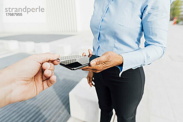 Hand eines Mannes mit Kreditkarte und der Tap-to-Pay-Methode bei einem Freiberufler