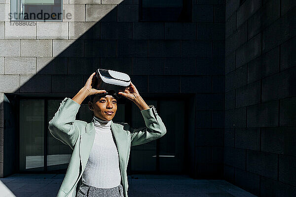 Junge Geschäftsfrau mit VR-Brille an einem sonnigen Tag