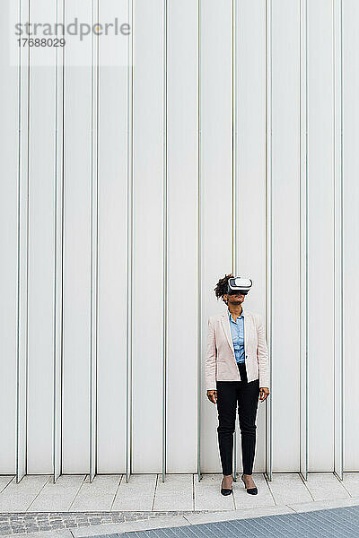 Geschäftsfrau trägt Virtual-Reality-Simulator vor weißer Wand