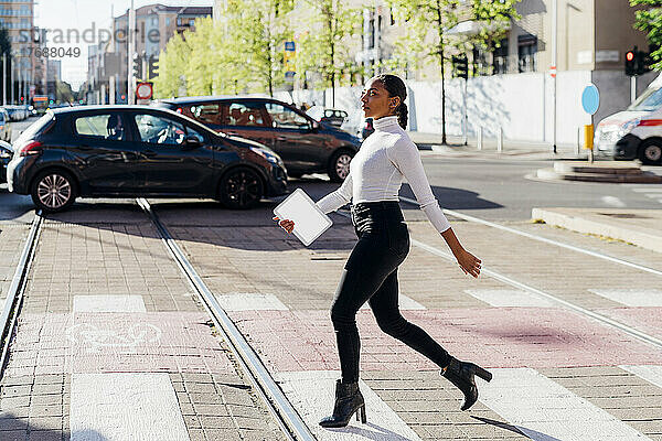 Junge Geschäftsfrau überquert an einem sonnigen Tag die Straße mit dem Auto