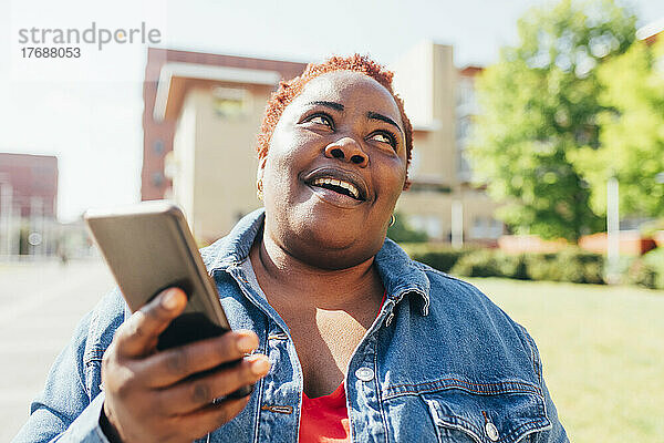 Lächelnde Frau mit Mobiltelefon in der Stadt