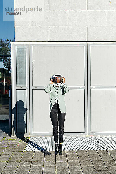 Geschäftsfrau mit Weltraumhelm springt vor Bürogebäude