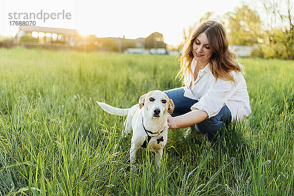 Lächelnde junge Frau mit Hund in der Natur
